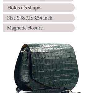 May include: Dark green leather crossbody bag with a crocodile texture. The bag has a flap closure and an adjustable strap. Dimensions are 9.5 x 7.1 x 3.54 inches. Features steel hardware and a magnetic closure.