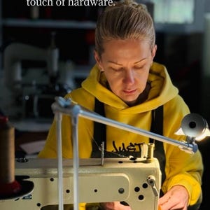 May include: A person in a yellow hoodie working on a sewing machine. The text in the image reads: "I handcraft each product from start to finish - from the first sketch to the final touch of hardware."