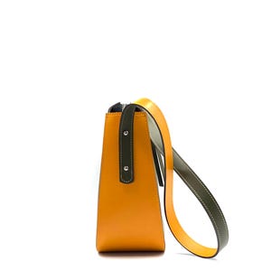 May include: A contemporary handbag in a trapezoid shape, with a bright orange body and a dark green accent on the handle attachment. The shoulder strap is a combination of yellow and olive green. The bag has a zip closure.