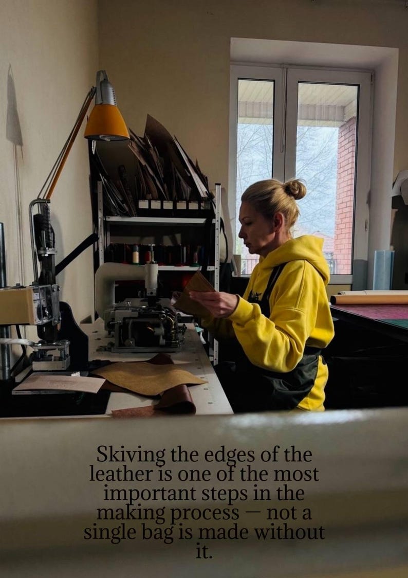 May include: A person in a yellow hoodie working with leather in a workshop. The text in the image reads: "Skiving the edges of the leather is one of the most important steps in the making process - not a single bag is made without it."