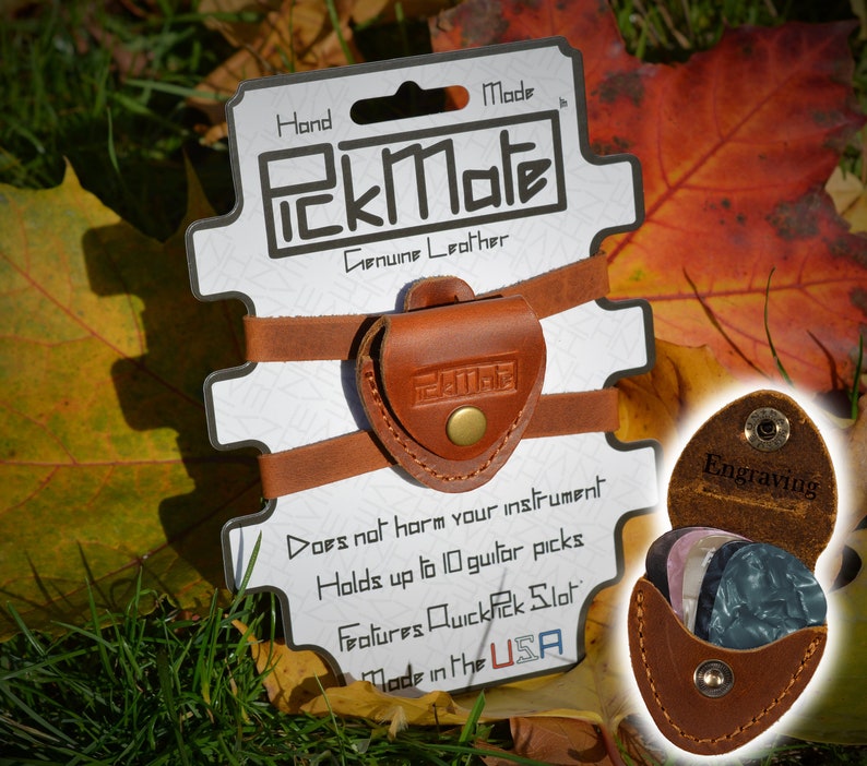 K&ouml;nnte beinhalten: Ein brauner PickMate Gitarrenplektrumhalter aus Leder mit dem Text "PickMate" und "Genuine Leather". Der Halter ist an einer wei&szlig;en Karte mit dem Text "Does not harm your instrument" und "Made in the USA" befestigt. Der Halter kann bis zu 10 Gitarrenplektren aufnehmen.