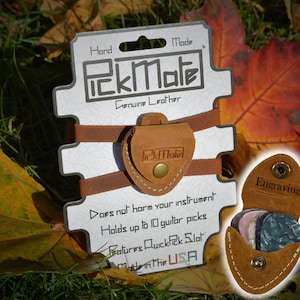 K&ouml;nnte beinhalten: Ein brauner PickMate Gitarrenplektrumhalter aus Leder mit dem Text "PickMate" und "Genuine Leather". Der Halter ist an einer wei&szlig;en Karte mit dem Text "Hand Made" und "Made in the USA" befestigt. Der Halter kann bis zu 10 Gitarrenplektren aufnehmen.