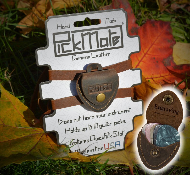 K&ouml;nnte beinhalten: Ein brauner PickMate Gitarrenplektrumhalter aus Leder mit Druckknopfverschluss, der mehrere Gitarrenplektren enth&auml;lt. Auf der Verpackung steht "Hand Made PickMate Genuine Leather" und "Made in the USA". Der Halter hat einen QuickPick-Schlitz und fasst bis zu 10 Plektren.