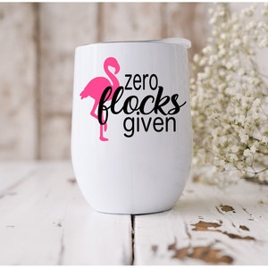 Puede incluir: Un vaso de acero inoxidable blanco con una silueta de flamenco rosa y el texto "zero flocks given".