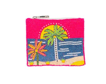 May include: A hot pink beaded coin purse with a tropical beach scene. The design features a yellow sun, two palm trees, blue water, and a sandy beach. The purse has a silver zipper.