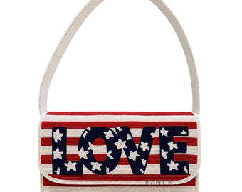 May include: A beaded clutch with a cream-colored strap. The clutch features a red and white striped pattern with the word "LOVE" in navy blue with white stars. The brand name "KANIK" is visible.