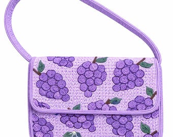 May include: A small, lavender beaded handbag with a matching handle. The bag features a repeating pattern of purple grapes with green leaves. The flap closure and edges are also trimmed in lavender.