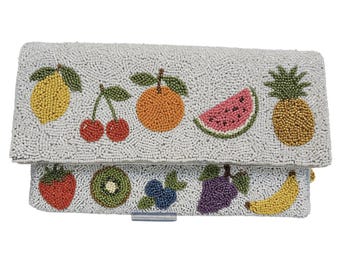 May include: A beaded clutch featuring a variety of colorful fruits. The fruits include a yellow lemon, red cherries, an orange, a watermelon slice, and a golden pineapple. Additional fruits include a red strawberry, a kiwi, blueberries, purple grapes, and a yellow banana.
