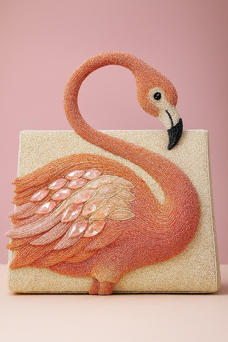 May include: A beaded flamingo-shaped clutch in shades of orange, peach, and cream. The flamingo features a black beak, a curved neck, and a body adorned with pink gemstone accents. The rectangular clutch has a textured, cream-colored base.
