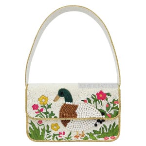 May include: A white beaded handbag with a duck and floral design. The duck features brown, white, and green beads. The bag has a white strap and gold trim. The design includes yellow and pink flowers and green foliage.