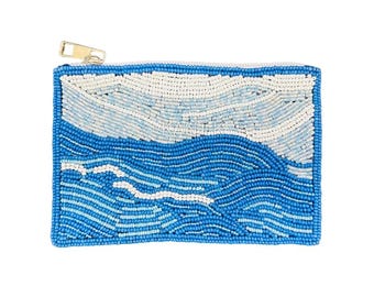 May include: A rectangular beaded pouch with a zipper closure. The pouch features a blue and white design depicting ocean waves. The zipper is gold-colored. The pouch is made of small, colorful beads.