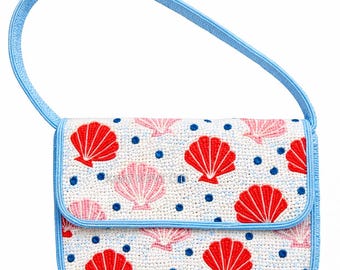 May include: A white beaded handbag with a blue handle and trim. The bag features a pattern of red and pink seashells and blue dots. The bag has a flap closure.