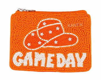 May include: Orange beaded coin purse with a white cowboy hat design and the text "GAMEDAY". The purse has a silver zipper and the brand name "KANTIK" is visible. The cowboy hat has white stars.