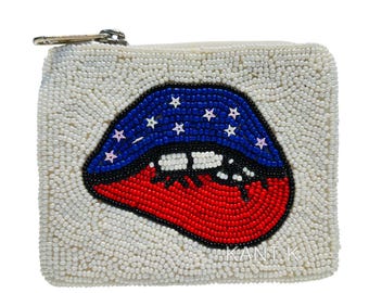 May include: A small, square, beaded coin purse with a zipper closure. The purse is covered in white beads and features a large, beaded design of lips in red, white, and blue, with stars on the blue portion. The text "KANT K" is visible.
