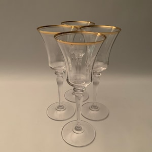 Könnte beinhalten: Set aus vier klaren Glas-Schnapsgläsern mit Stiel und goldfarbenem Rand.