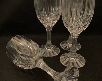 May include: Set of four clear glass wine glasses with a cut crystal design. The glasses have a tall, slender stem and a wide bowl.