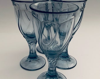 Può includere: Set di quattro bicchieri da vino in vetro blu con un design a spirale. I bicchieri hanno una base trasparente e una ciotola larga.
