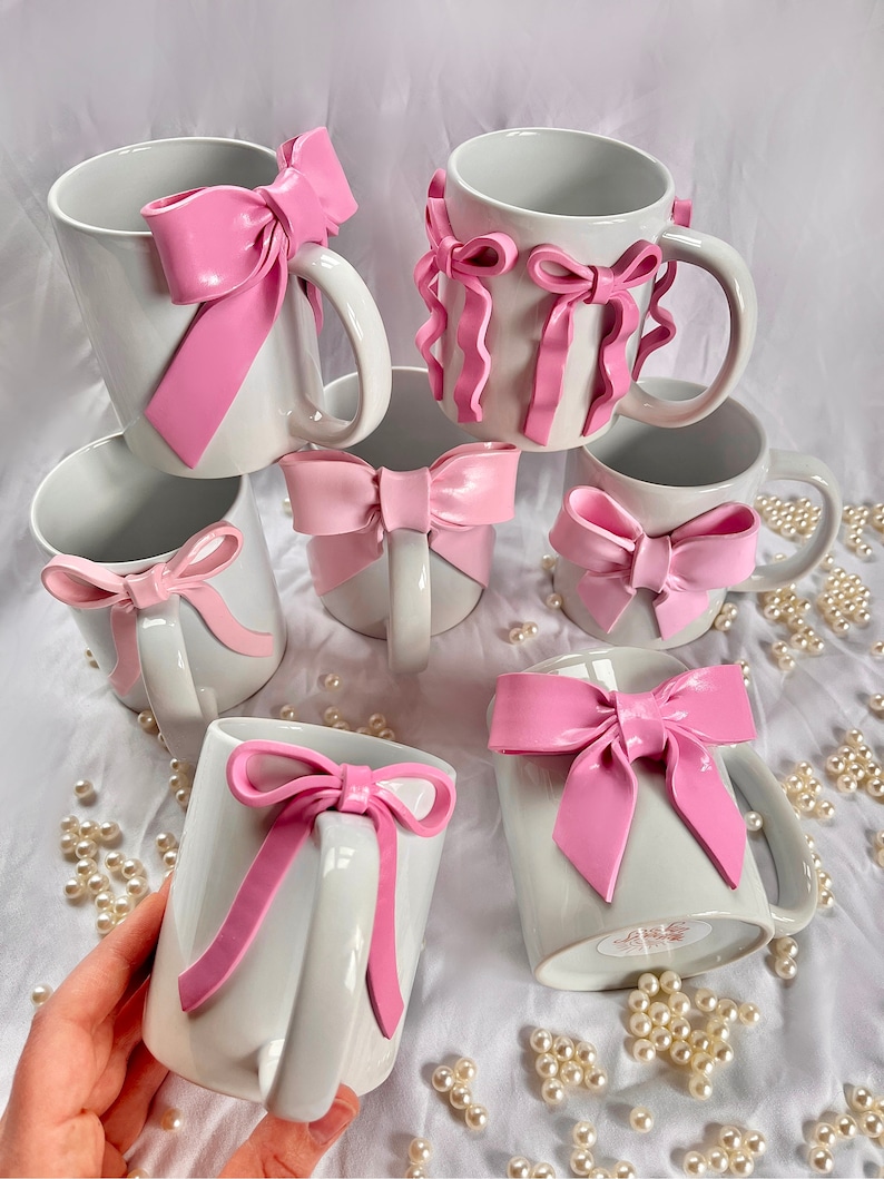 Pu&ograve; includere: Set di sei tazze in ceramica bianca con fiocchi rosa. I fiocchi sono realizzati in un materiale morbido e flessibile e sono fissati alle tazze con un adesivo resistente. Le tazze sono perfette per aggiungere un tocco di fantasia a qualsiasi cucina o ufficio.