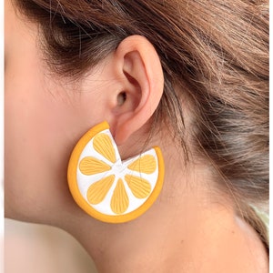 May include: A pair of yellow and white lemon slice earrings. The earrings are made of a lightweight material and have a fun, summery design.