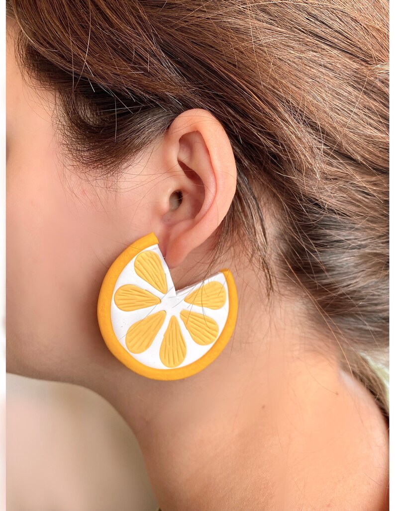 May include: A pair of yellow and white lemon slice earrings. The earrings are made of a lightweight material and have a fun, summery design.