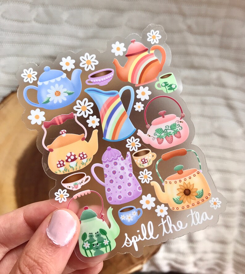 May include: A clear sticker sheet with colorful teapots, cups, and flowers. The text "spill the tea" is written in cursive at the bottom of the sheet.