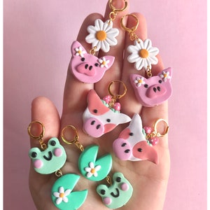 Pu&ograve; includere: Un set di sei paia di orecchini fatti a mano in pasta polimerica. Gli orecchini presentano una variet&agrave; di simpatici disegni di animali, tra cui maiali, mucche e rane. Gli orecchini sono tutti attaccati ad anelli dorati.