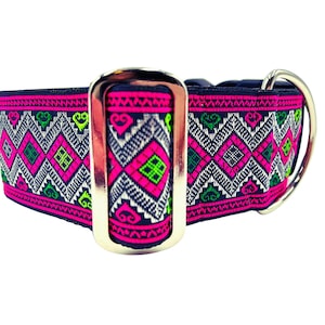 May include: A black and white patterned dog collar with pink and green accents. The collar has a silver buckle and a silver D-ring.