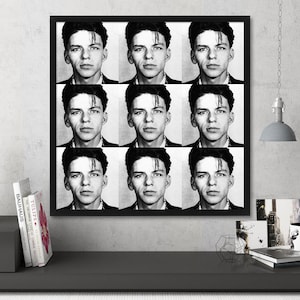 May include: Black and white framed artwork featuring a grid of nine identical portraits of a man with dark hair and a serious expression. The artwork is displayed on a gray wall above a dark gray surface.