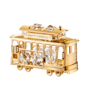 Puede incluir: Una réplica en miniatura de color dorado de un tranvía de San Francisco con detalles de cristal. El tranvía tiene la inscripción "POWELL & HYDE St." en el lateral y "POWELL, MARKET AND HYDE ST." en la parte posterior.