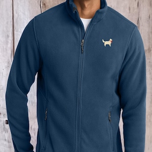 May include: A dark blue fleece jacket with a full-length front zipper, a high collar, and two zippered side pockets. The left chest features a small embroidered graphic of a light-colored dog wearing a red collar against the blue fabric.
