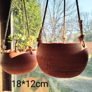 Peut inclure: Deux pots suspendus en terre cuite avec des cordes. Le plus grand pot mesure 18 pouces par 12 pouces.