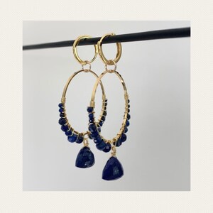 May include: Gold hoop earrings with blue gemstone beads and teardrop dangles.