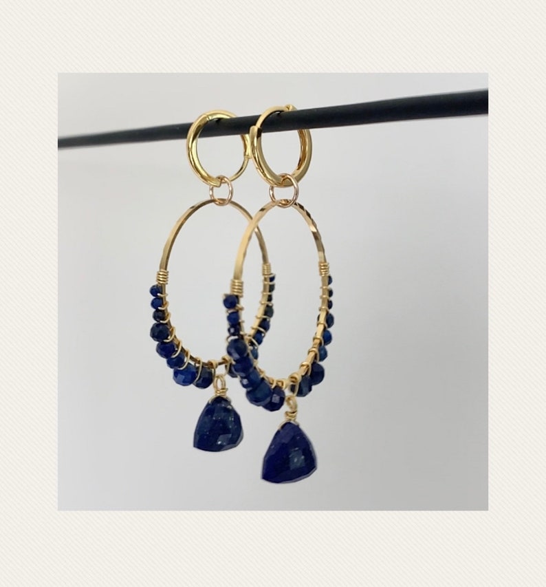 May include: Gold hoop earrings with blue gemstone beads and teardrop dangles.
