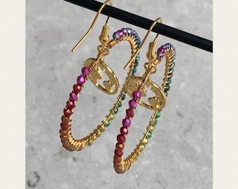 May include: A pair of gold hoop earrings with a rainbow gradient of beads and a world map charm.