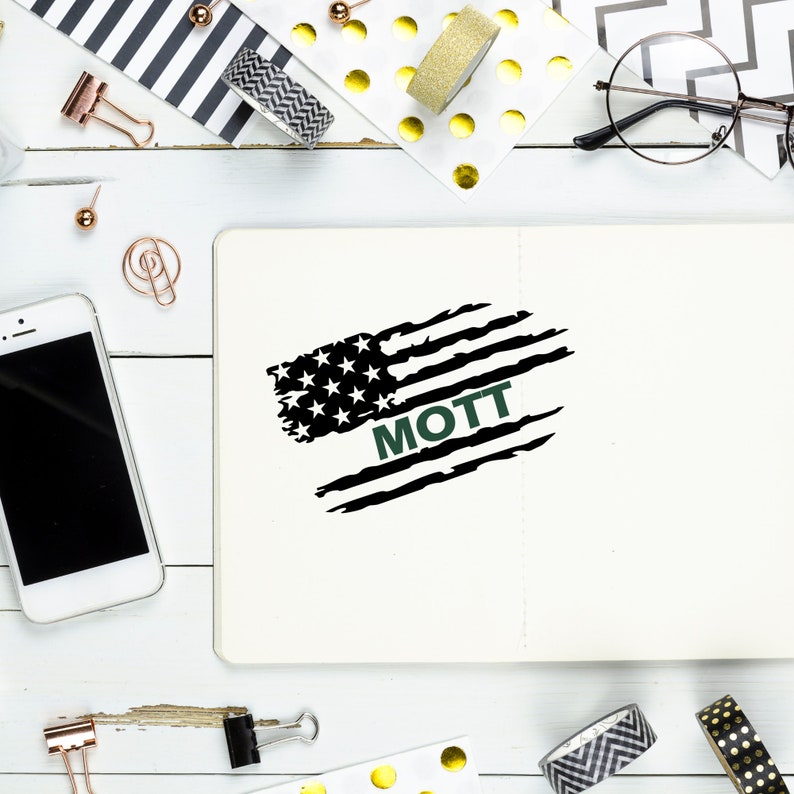 Puede incluir: Un cuaderno blanco con un dise&ntilde;o de bandera estadounidense desgastada en blanco y negro con la palabra "MOTT" en texto verde.