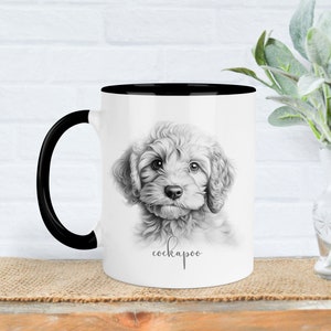 Può includere: Tazza in ceramica bianca con bordo e manico neri. La tazza presenta un'illustrazione in bianco e nero di un cucciolo di cockapoo con la parola "cockapoo" stampata sotto l'immagine.