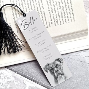 Peut inclure: Un marque-page gris et blanc avec un gland noir. Le marque-page présente une illustration en noir et blanc d'un boxer et le texte "Bella" et "Si j'aime, c'est à moi".