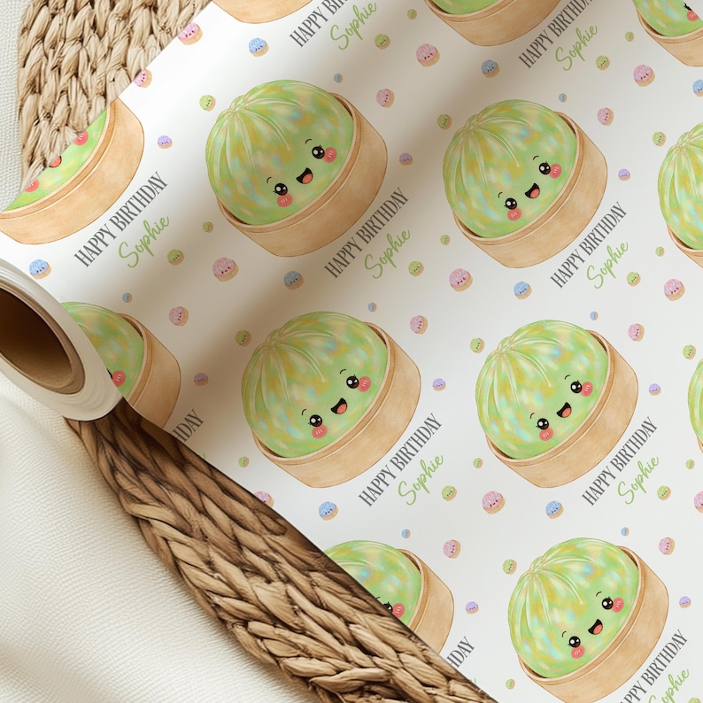Op de afbeelding: Wit cadeaupapier met een herhalend patroon van cartoon dim sum in bamboe stoommandjes. De dim sum zijn lichtgroen met lachende gezichten. De tekst "HAPPY BIRTHDAY Sophie" wordt herhaald.