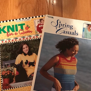 May include: Two knitting pattern books. The first book is titled "Knit for a Queen" and features a woman wearing a yellow sweater with a black dog on it. The second book is titled "Spring Casuals" and features a woman wearing a colorful striped sleeveless sweater.