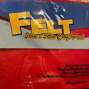 May include: A package of red felt for craft projects. The package reads "FELT" in large yellow letters, with the text "36in x 36in Craft Pack" below. The package also states the felt is 36 inches by 36 inches.