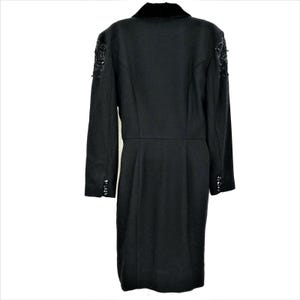 Puede incluir: Un vestido negro de manga larga con cuello de terciopelo y adornos de cuentas en los hombros y los pu&ntilde;os.