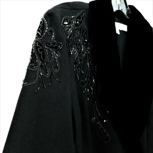 Puede incluir: Una chaqueta negra con cuello de terciopelo y adornos florales de cuentas en los hombros.