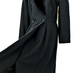 Puede incluir: Un vestido negro de manga larga con cierre de doble botonadura y un dise&ntilde;o de cuentas en el cuello.
