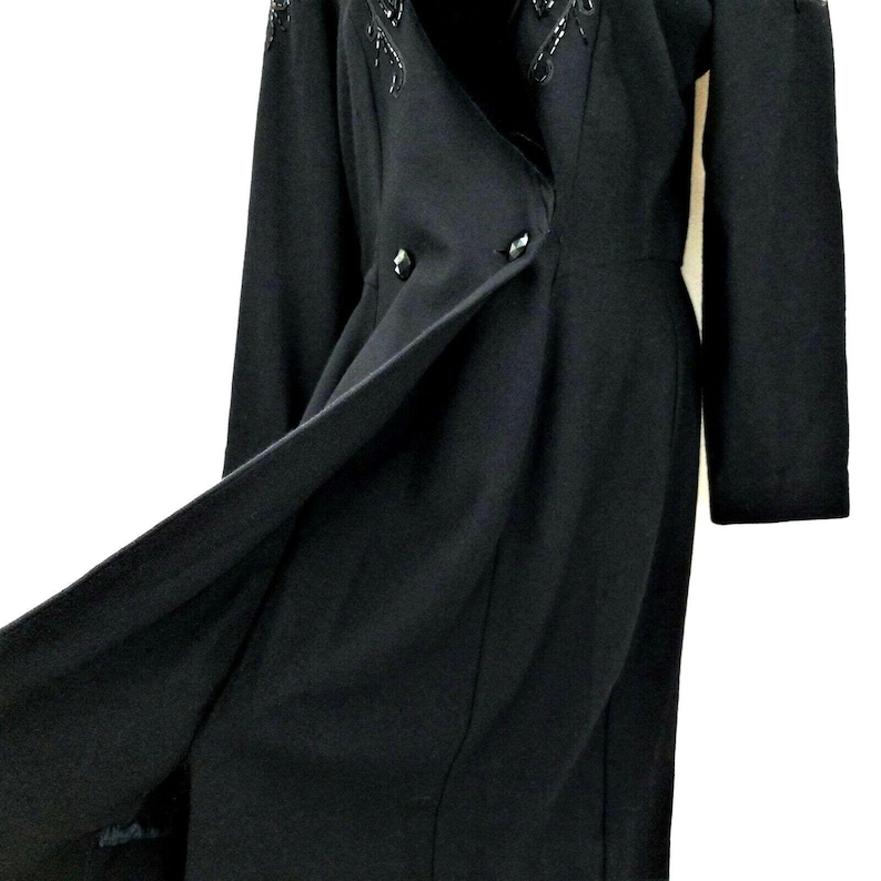 Puede incluir: Un vestido negro de manga larga con cierre de doble botonadura y un dise&ntilde;o de cuentas en el cuello.