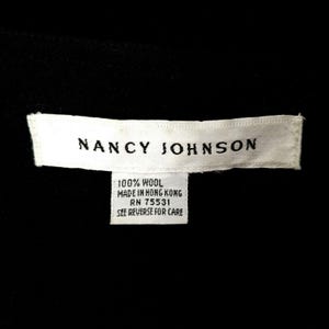 Puede incluir: Etiqueta blanca con texto negro que dice "NANCY JOHNSON" y "100% LANA HECHO EN HONG KONG RN 75531 VER EL DORSO PARA EL CUIDADO"