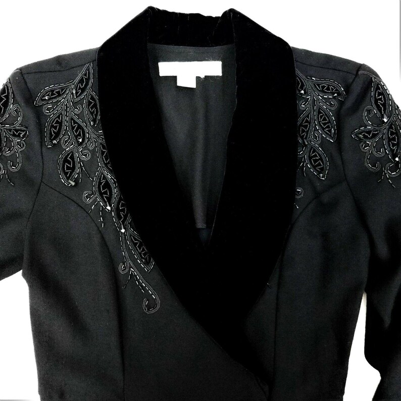 Puede incluir: Una chaqueta negra con cuello de terciopelo y bordados de cuentas en los hombros.