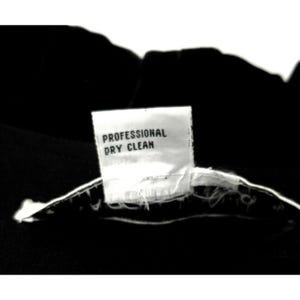 Puede incluir: Una etiqueta de cuidado blanca con el texto "Professional Dry Clean" sobre un fondo negro.