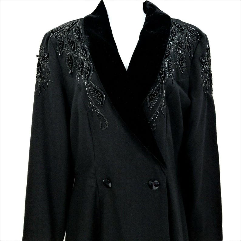 Puede incluir: Una chaqueta negra de doble botonadura con cuello de terciopelo y adornos de cuentas.
