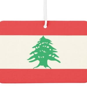 May include: A car air freshener featuring the flag of Lebanon. The flag is red, white and green with a green cedar tree in the centre.