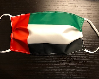 May include: A white face mask with the flag of the United Arab Emirates printed on it. The mask has red, white, green, and black stripes.